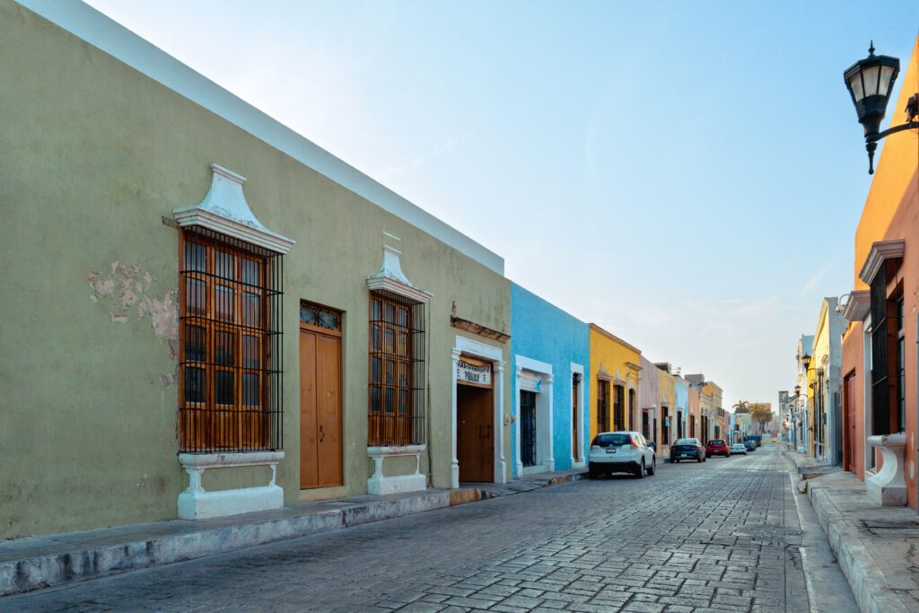 Residential street in Campeche with trees, bikes, cafés, and modern homes.