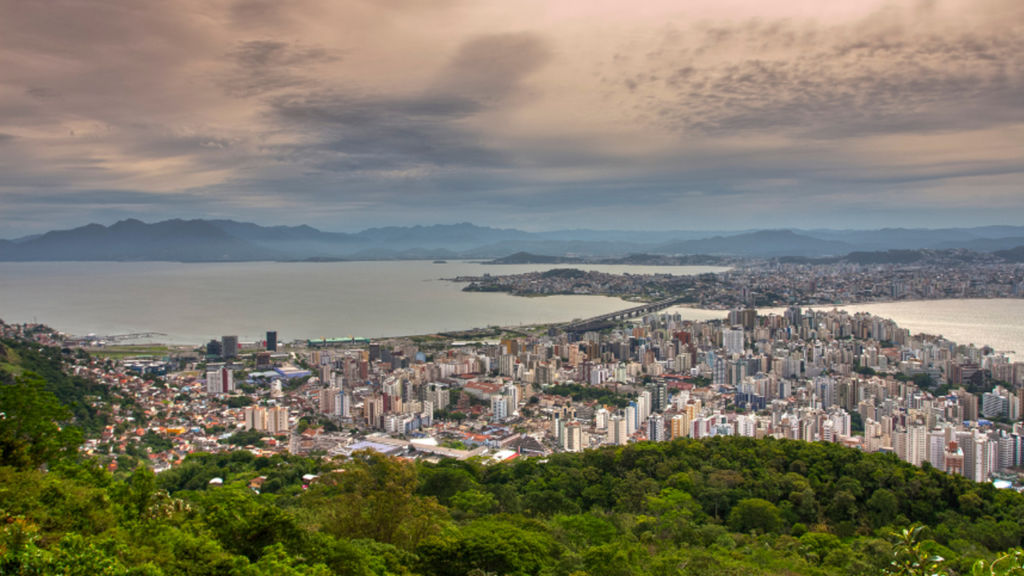 Aerial view of Florianópolis showing coastal neighborhoods, beaches, waterfront developments, and the lifestyle popular with expats and digital nomads.