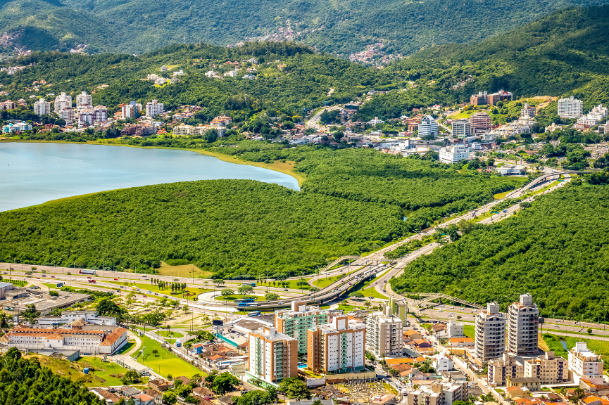 Aerial view of Florianópolis, Brazil, showcasing its coastline, lush green hills, and pleasant subtropical climate.